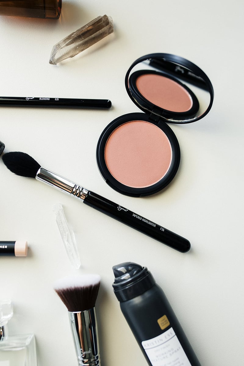 A flat lay of a highlighter compact, a tapered brush, a crystal point and an eye blending brush